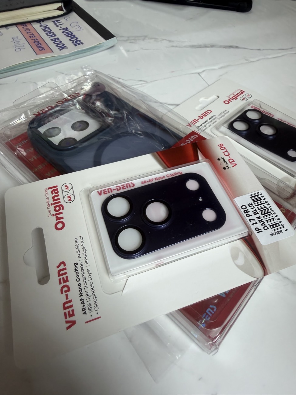 Camera lens protectors with anti-glare nano coating packaged for the latest iPhone models on the Techmart counter.